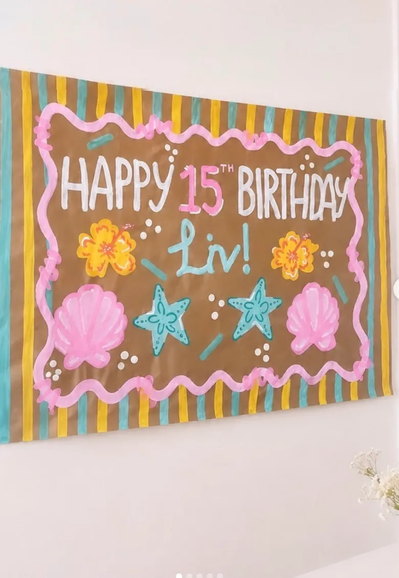 Striped 15th birthday banner with shells and starfish hung on a wall